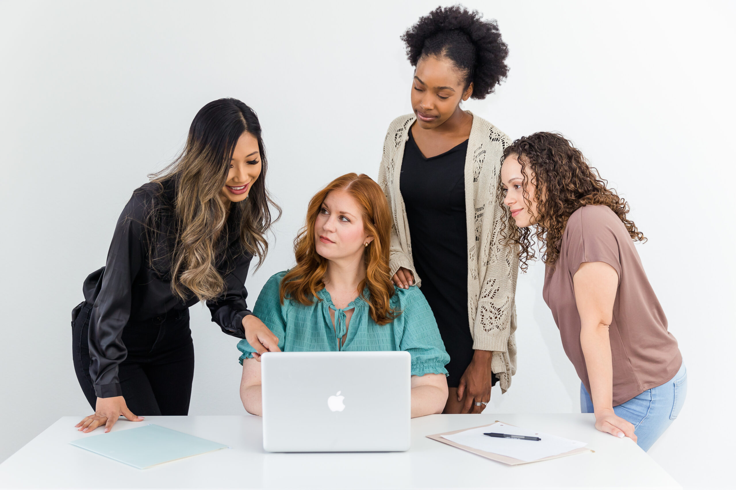 Four women standing around a computer to prepare their store for upcoming sales