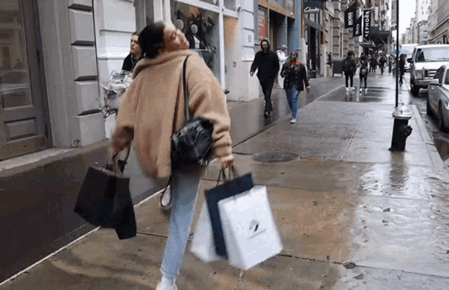 GIF of a woman skipping on a sidewalk with shopping bags in hand