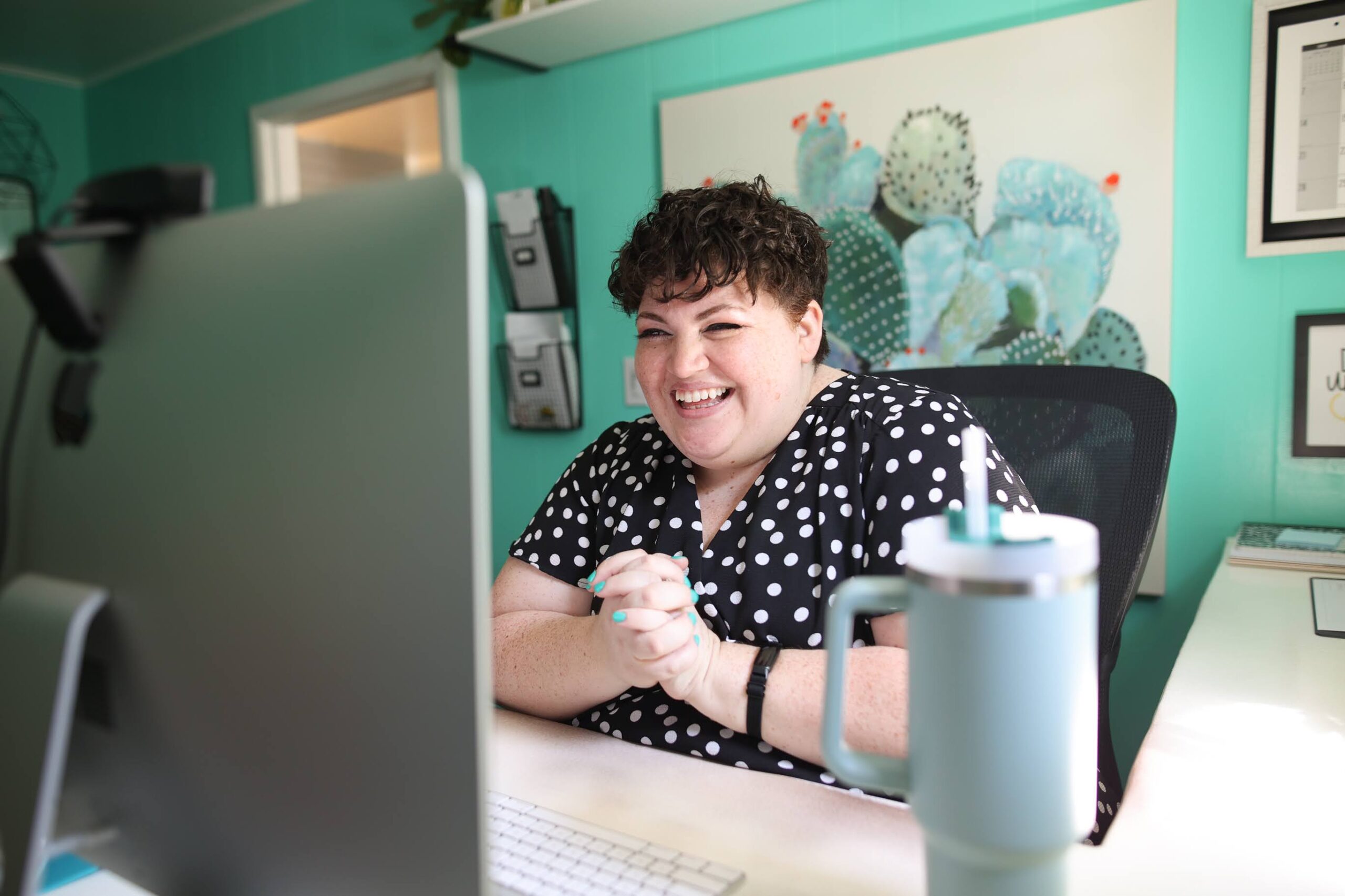 Picture of me at my desk decked out in teal, which I decided during my process of branding.